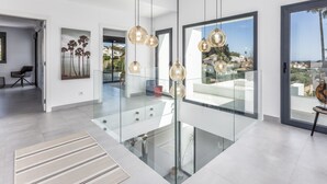 Ein modernes Interieur mit einer Glasstufenkonstruktion, Pendelleuchten und Blick auf die Stadt.