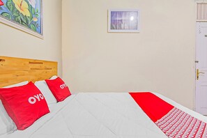 A hotel room with a wooden headboard, two red pillows, a white bedspread, a small window, and a white door. - Hotel O New Bunga Sonsang Homestay Syariah (Padang)