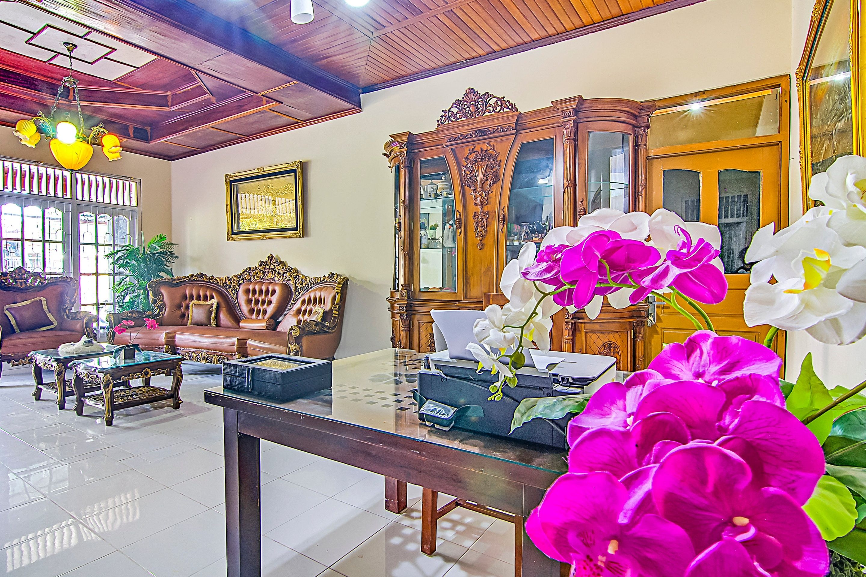 A well-furnished living room with a glass coffee table, leather sofas, and a wooden cabinet.