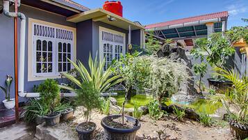 A courtyard with potted plants, a small pond, and a building with a red roof and white windows.