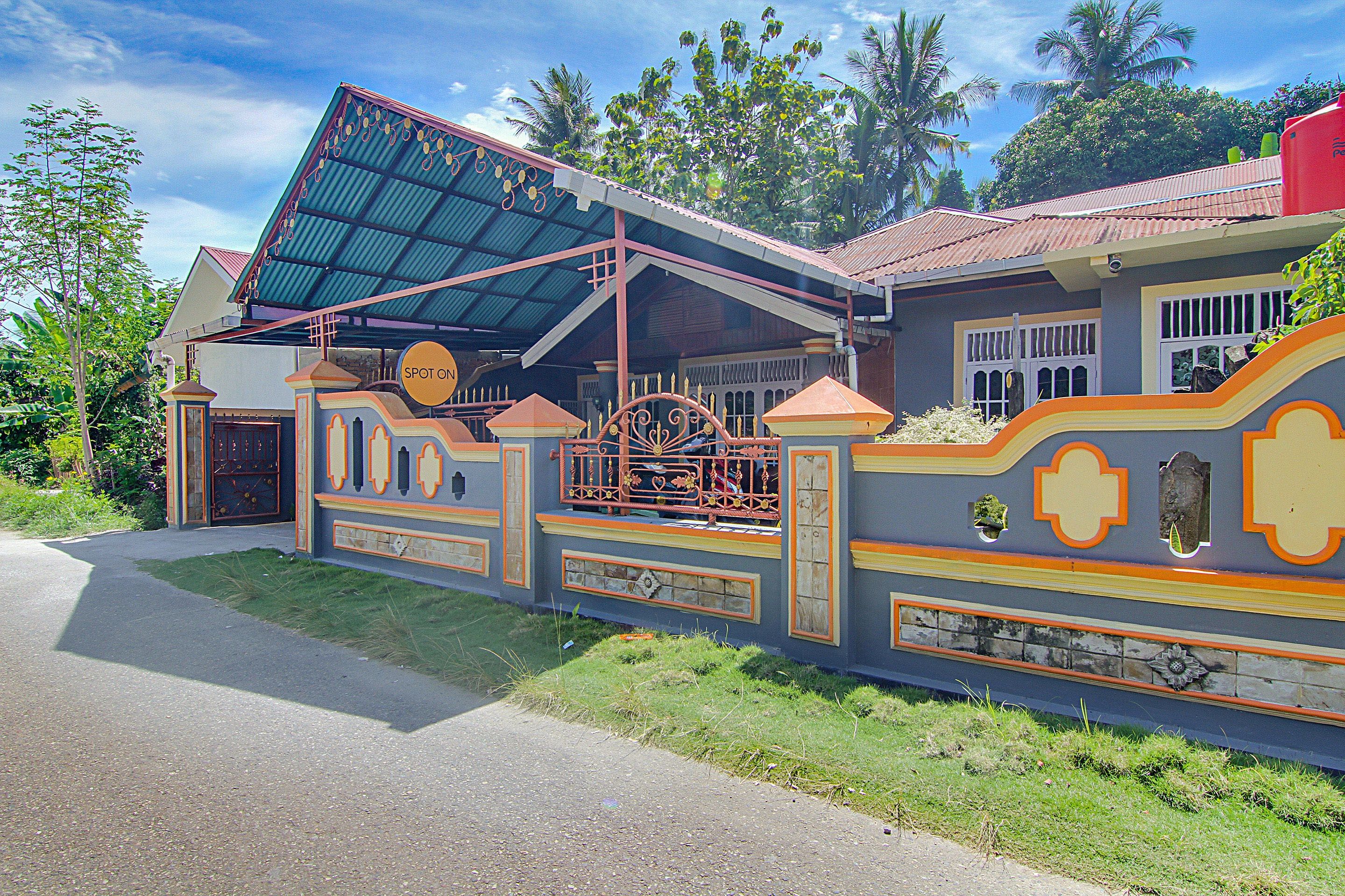 Una casa con un estilo arquitectónico distintivo, que cuenta con un porche cubierto, un acceso con reja y un muro decorativo con patrones geométricos.