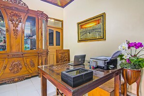 A wooden cabinet with glass doors, a framed picture on the wall, a desk with a laptop, printer, and potted orchid. - Hotel O New Bunga Sonsang Homestay Syariah (Padang)