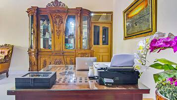 A room with a wooden cabinet, a laptop, a printer, and a potted orchid.