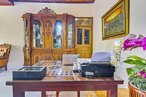 Una habitació amb un armari de fusta, un ordinador portàtil, una impressora i una orquídia en test.