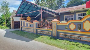 A house with a distinctive architectural style, featuring a covered porch, a gated entrance, and a decorative wall with geometric patterns. - Hotel O New Bunga Sonsang Homestay Syariah (Padang)