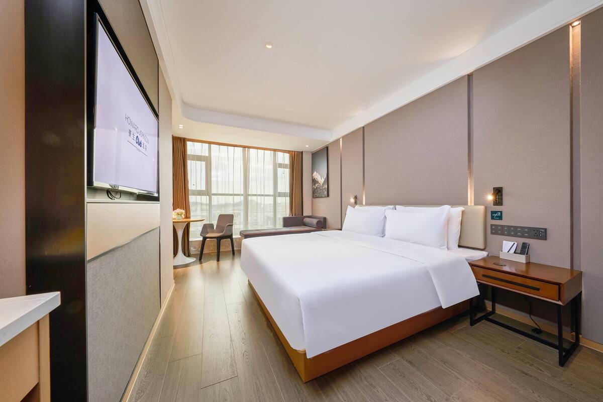 Une chambre d’hôtel avec un grand lit, un bureau, une chaise et un écran de télévision affichant un message.