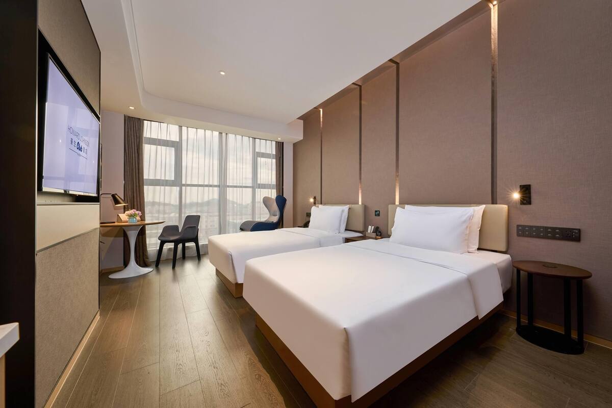 Une chambre d’hôtel avec deux lits, un bureau, une chaise et un écran de télévision.