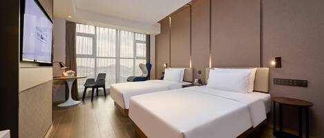 A hotel room with two beds, a desk, a chair, and a TV screen.