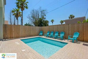 Una piscina con valla de madera y varias sillas.