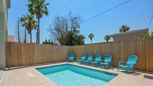 A rectangular swimming pool with a wooden fence and chairs around it. - Beach Retreat w/ Pool | 4 Bedrooms • Sleeps 12 (South Padre Island)