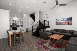 Un salon moderne avec un canapé gris, une table basse en bois et un tapis coloré.