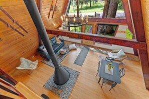 Ein gemütliches Blockhaus-Interieur mit einem großen Kamin, Holzwänden, einem Essbereich und Blick ins Freie.