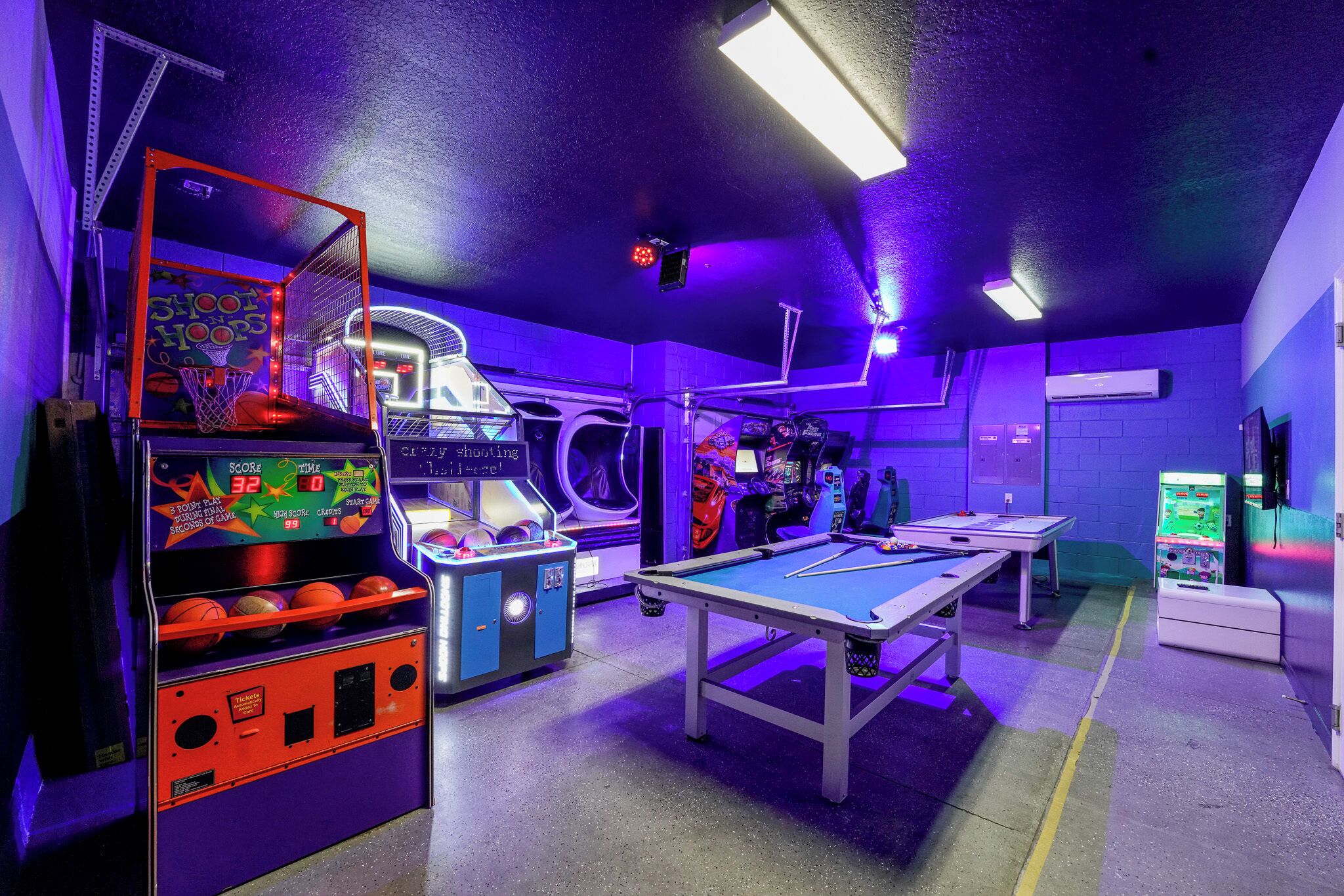 Un espacio recreativo con mesa de billar, baloncesto y máquina de pinball.