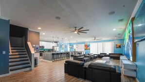 A spacious living area with a kitchen, a dining area, and a seating area with sofas and a coffee table. - Global Bowling Villa, 1GB wifi, video wall TV, private/heated pool, sleeps 34 (Davenport)