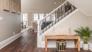 A staircase with a black railing, a wooden bench with a cushion, and a potted plant.