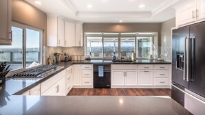 A modern kitchen with white cabinetry, a black dishwasher, and a stainless steel refrigerator.
