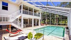 Une piscine extérieure couverte avec un toit en verre, un espace patio doté de chaises longues et un escalier menant à un niveau supérieur.