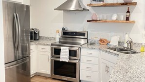Una cocina moderna con electrodomésticos de acero inoxidable, armarios blancos y encimera de granito.