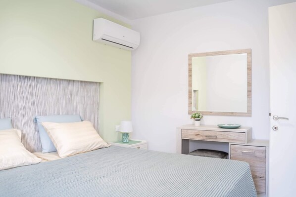 Un dormitorio con cama, mesita de noche, lámpara, espejo y un armario pequeño.