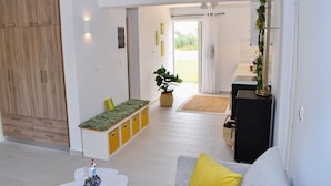 Ein modernes Wohnzimmer mit Sofa, Couchtisch, Pflanze und einem durchgehenden Durchgang zur Küche.