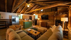 Interno di una baita di legno con cucina, sala da pranzo e soggiorno.