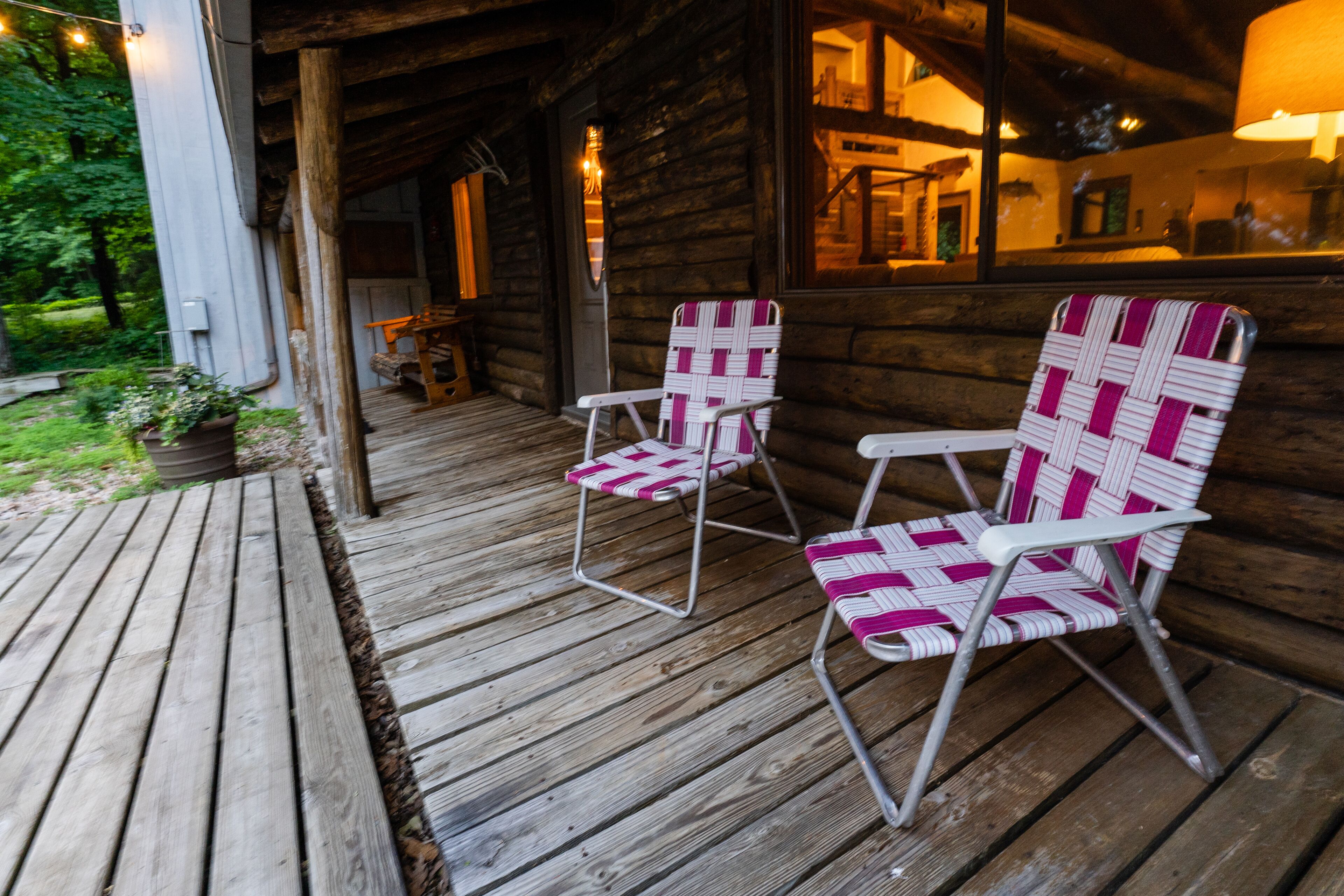 A wooden porch with two wicker chairs and a wooden deck.