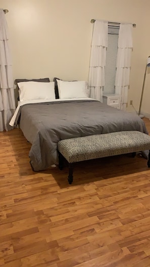 A bedroom with a bed, a bench, and curtains.