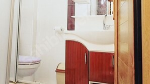 Een badkamer met een toilet, een wastafel en een spiegel.