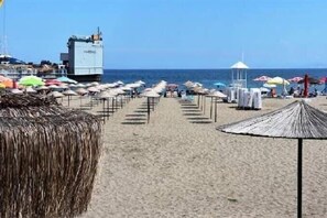 A beach with rows of sun umbrellas and beach chairs, a lifeguard tower, and a clear view of the sea. - Apartment located 300 m from the beach (Süleymanpaşa Tekirdağ)