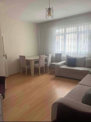 A modern living room with a dining area, a sofa, and a hanging light fixture. - Apartment 300 m from the beach (Süleymanpaşa Tekirdağ)