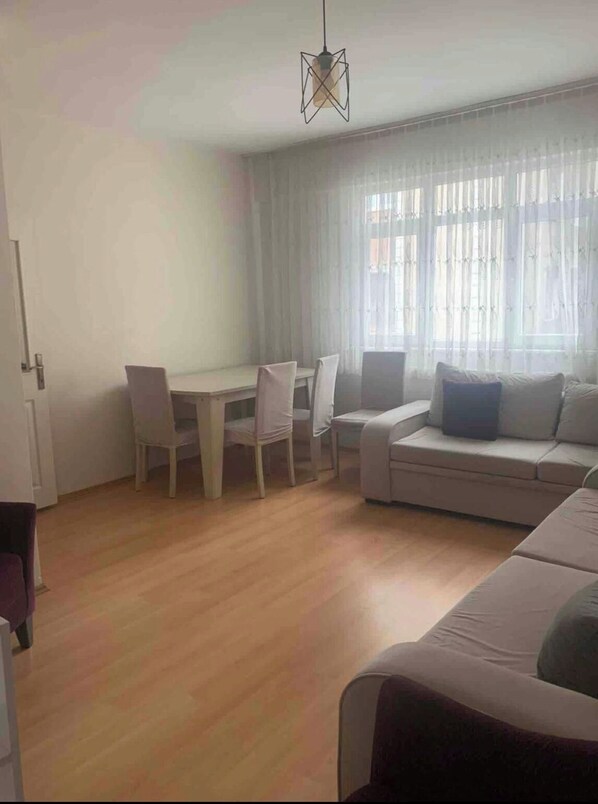 A living room with a sofa, a dining table with chairs, and a hanging light fixture. - Apartment located 300 m from the beach (Süleymanpaşa Tekirdağ)