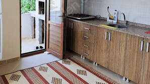 Een keuken met houten kastjes, een betegelde achterwand en een inbouwfornuis.