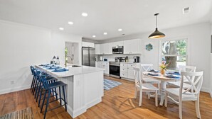 A modern kitchen with white cabinets, a central island, and blue bar stools. - 4 bedroom pool home 1 block from the Beach! (Myrtle Beach)