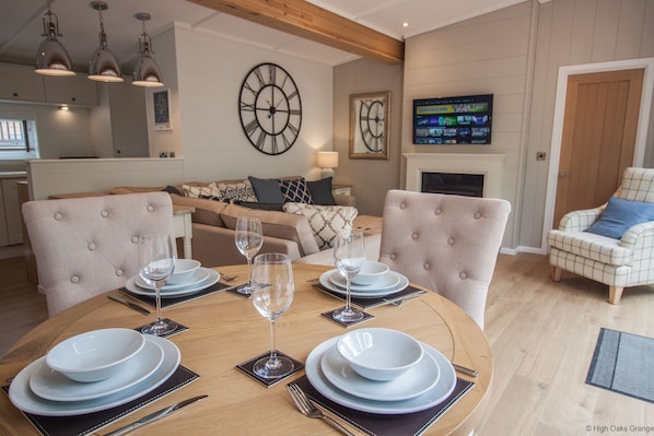 Een eetgedeelte met een ronde tafel voor vier personen, een bank achterin en een televisie aan de muur.
