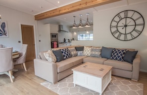 Een moderne woonkamer met een modulaire bank, een salontafel en een grote wandklok.