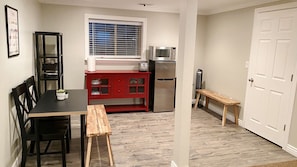 A compact kitchen with a dining table, chairs, a red cabinet, a refrigerator, a microwave, and a bench. - Entire Modern Basement Apt in Sandy—1 min to I-15 (Sandy)