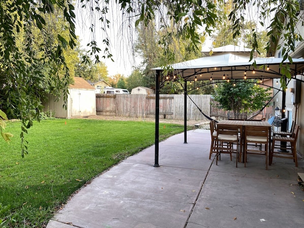 A backyard patio with a pergola, outdoor seating, and a well-maintained lawn. - Entire Modern Basement Apt in Sandy—1 min to I-15 (Sandy)