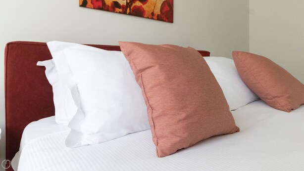 A bed with white and pink pillows and a red headboard. - Italianway Easy - Plinio 64 (Milan)