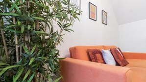 A living room with a sofa, a large green plant, and two framed pictures on the wall. - Italianway Easy - Plinio 64 (Milan)