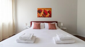 Ein Hotelzimmer mit einem großen Bett, zwei Nachttischen, einem Bild an der Wand und Handtüchern auf dem Bett.
