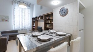 A dining area with a table set for four, a bookshelf, and a clock on the wall. - Italianway Easy - Pisino 5 (Milan)