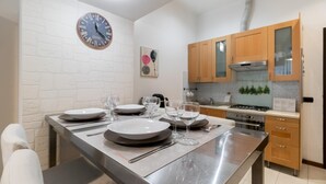 A modern kitchen with wooden cabinets, a stainless steel countertop, and a clock on the wall. - Italianway Easy - Pisino 5 (Milan)