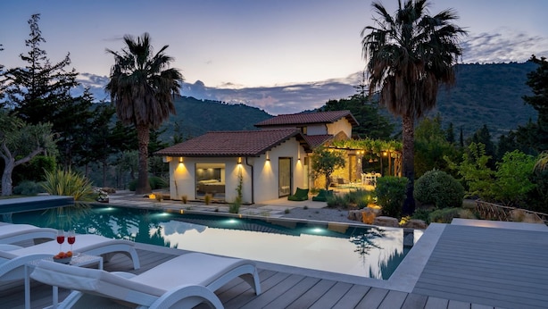 A modern house with a swimming pool, outdoor seating, and a mountain backdrop. - Villa Charme 6 in Pollina (Pollina)