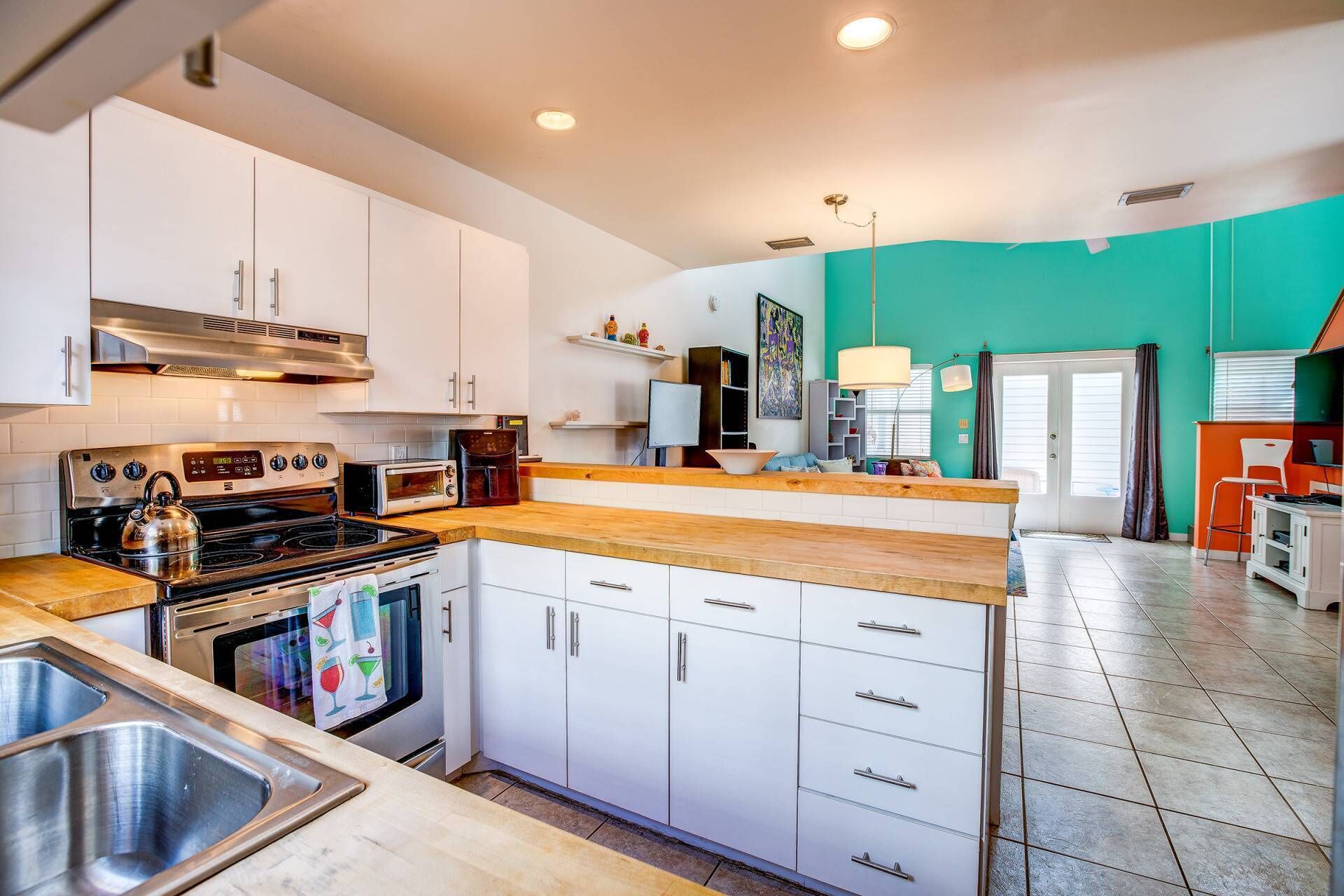 A modern kitchen with white cabinets, stainless steel appliances, and a wooden countertop.