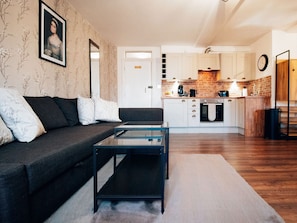 A modern living room with a sofa, coffee table, and a kitchen in the background.