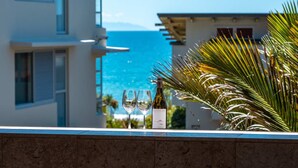 A terrace with a view of the sea, a bottle of wine, and two glasses. - The Sands - Apartment 12 Onetangi Beach (Waiheke Island)