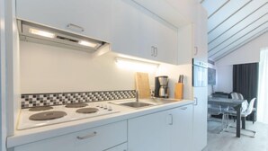 Una cocina moderna con armarios blancos, salpicadero de azulejos blanco y negro, estufa y cafetera.