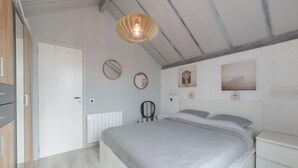 Un dormitorio con cama, mesitas de noche, un radiador, un espejo y cuadros en la pared.