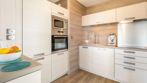 Una cocina moderna con armarios blancos, electrodomésticos de acero inoxidable y piso de madera.