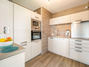 Een koelkast, een oven, een vaatwasser, kookgerei, borden en bestek